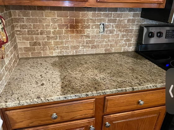 badly stained granite countertop and travertine backsplash
